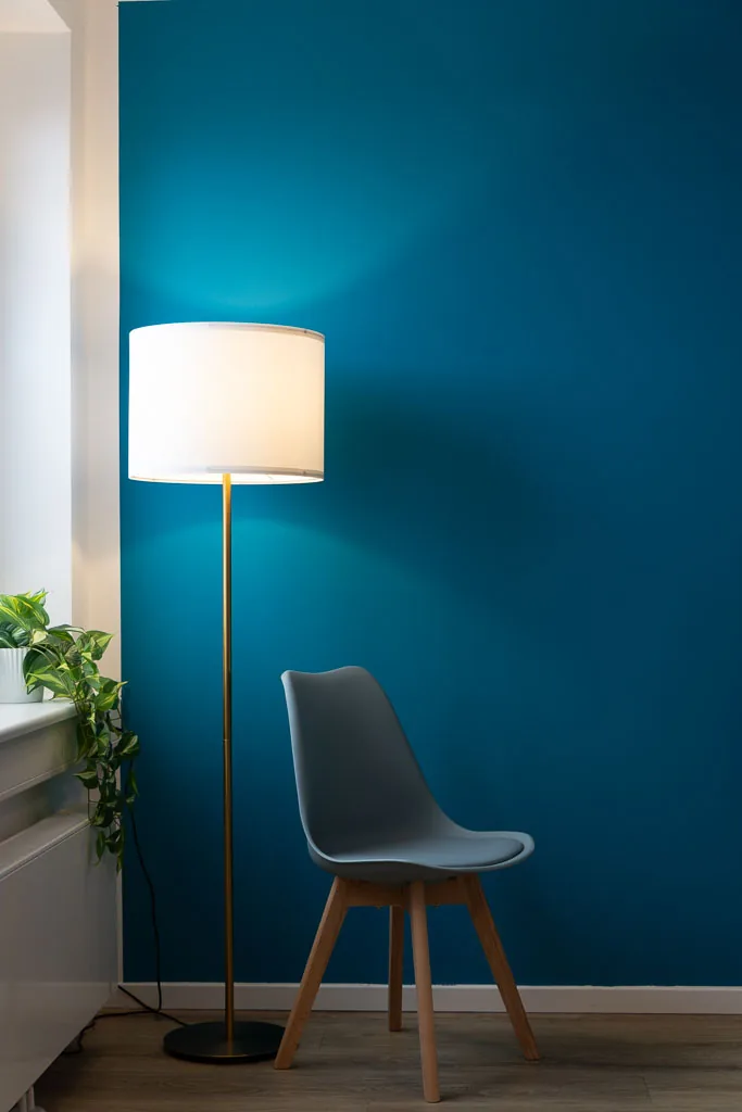 Stehlampe und Sessel vor blauer Wand im Behandlungsraum