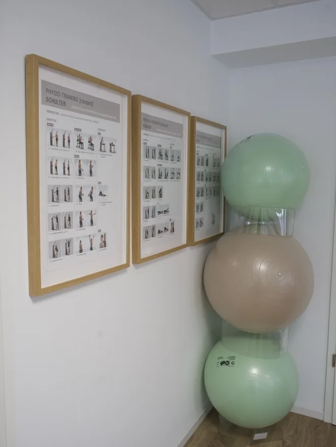 Gymnastikbälle und gerahmte Übungstafeln an der Wand